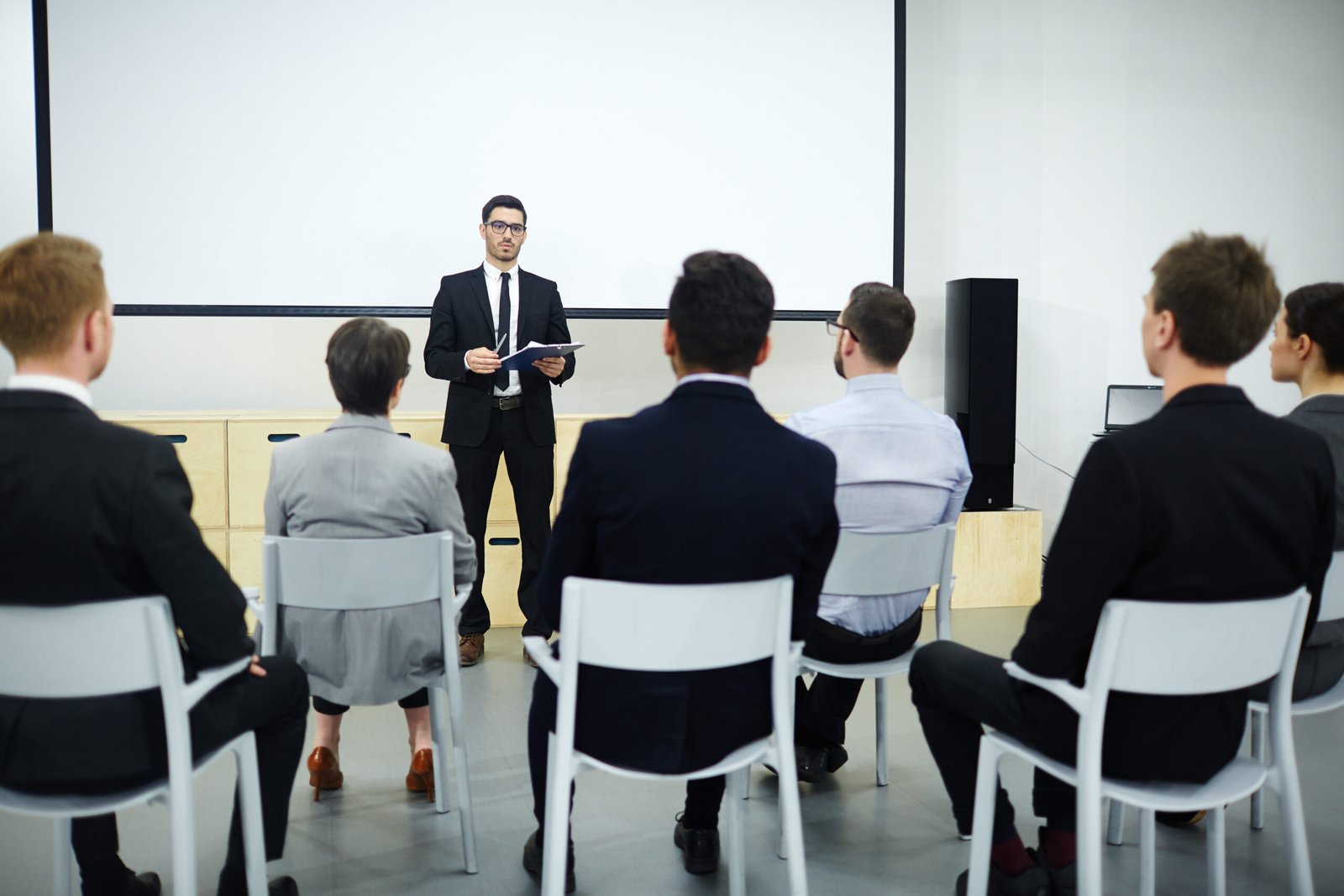 Rear view of audience listening to speech of successful business professional